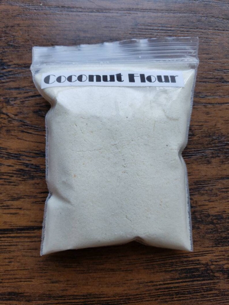 Peut inclure: Un sac en plastique transparent rempli de farine de coco blanche. Le sac porte une &eacute;tiquette blanche sur laquelle est inscrit "Coconut Flour".