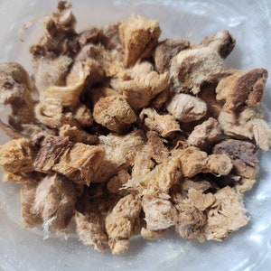 Puede incluir: Primer plano de un bol lleno de trozos de jengibre secos, de color marr&oacute;n claro y beige.