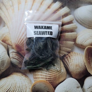 Puede incluir: Una peque&ntilde;a bolsa de pl&aacute;stico transparente con una etiqueta blanca que dice "Wakame Seaweed" y contiene algas secas.