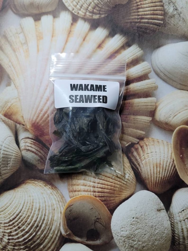 Puede incluir: Una peque&ntilde;a bolsa de pl&aacute;stico transparente con una etiqueta blanca que dice "Wakame Seaweed" y contiene algas secas.