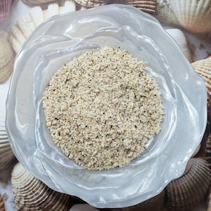 May include: A white bowl with a textured surface holds a pile of finely ground, light brown powder.