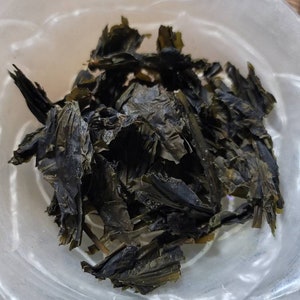 Puede incluir: Un bol de algas secas, de color verde oscuro, sobre un fondo marr&oacute;n claro.