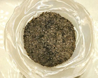 May include: A clear glass bowl filled with a large amount of dried, dark green, leafy herbs.