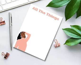May include: A white notepad with the text "All The Things" in pink lettering. A pink illustration of a woman with brown hair is in the bottom left corner.
