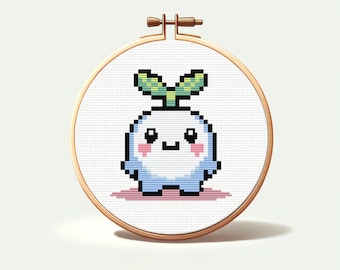 May include: A white and blue cross-stitch embroidery hoop with a cute cartoon plant character with a green stem and leaves. The character has a white body with pink cheeks and a blue bottom.