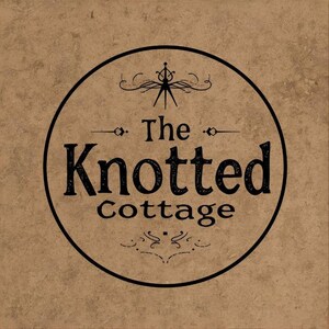 May include: A circular logo featuring the words "The Knotted Cottage" in a black, vintage font. The logo is set against a textured, tan background. Decorative flourishes and a stylized emblem are above and below the text.