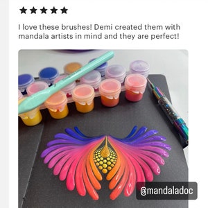 Op de afbeelding: Een close-up van een kleurrijk mandala-ontwerp gemaakt met verf en een set verfpotjes en kwasten. Het ontwerp heeft een regenboogkleurige gradi&euml;nt, waaronder paars, roze, oranje en geel. De verfpotjes zijn gelabeld met "Thoughtful Dots". De afbeelding bevat ook de tekst "@mandaladoc".