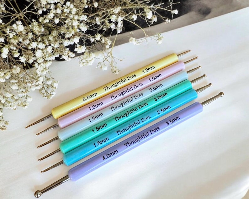May include: Set of seven colorful dotting tools with different sized tips, ranging from 0.5mm to 4.0mm. The tools are labeled with their size and the brand "Thoughtful Dots".