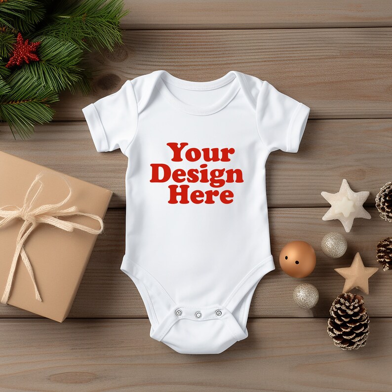 May include: A white baby onesie with the text "Your Design Here" in red. The onesie is surrounded by holiday decorations, including a wrapped gift, pine branches, and ornaments. The onesie is made of soft material.