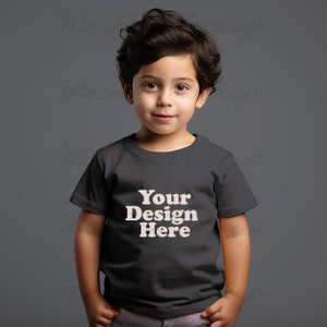 K&ouml;nnte beinhalten: Ein kleines Kind tr&auml;gt ein schwarzes T-Shirt mit dem Aufdruck "Your Design Here" in wei&szlig;.