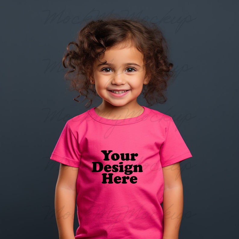 K&ouml;nnte beinhalten: Ein kleines Kind tr&auml;gt ein pinkfarbenes T-Shirt mit dem Aufdruck "Your Design Here" in Schwarz.