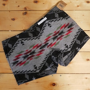 May include: Gray and black patterned shorts with red, green, and white accents. The shorts are made of a soft, fuzzy material.