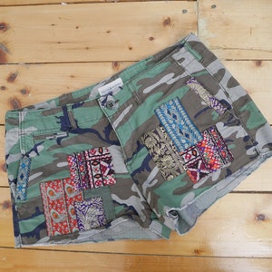 May include: Camouflage shorts with colorful patchwork details. The shorts are made of a cotton blend and have a relaxed fit.