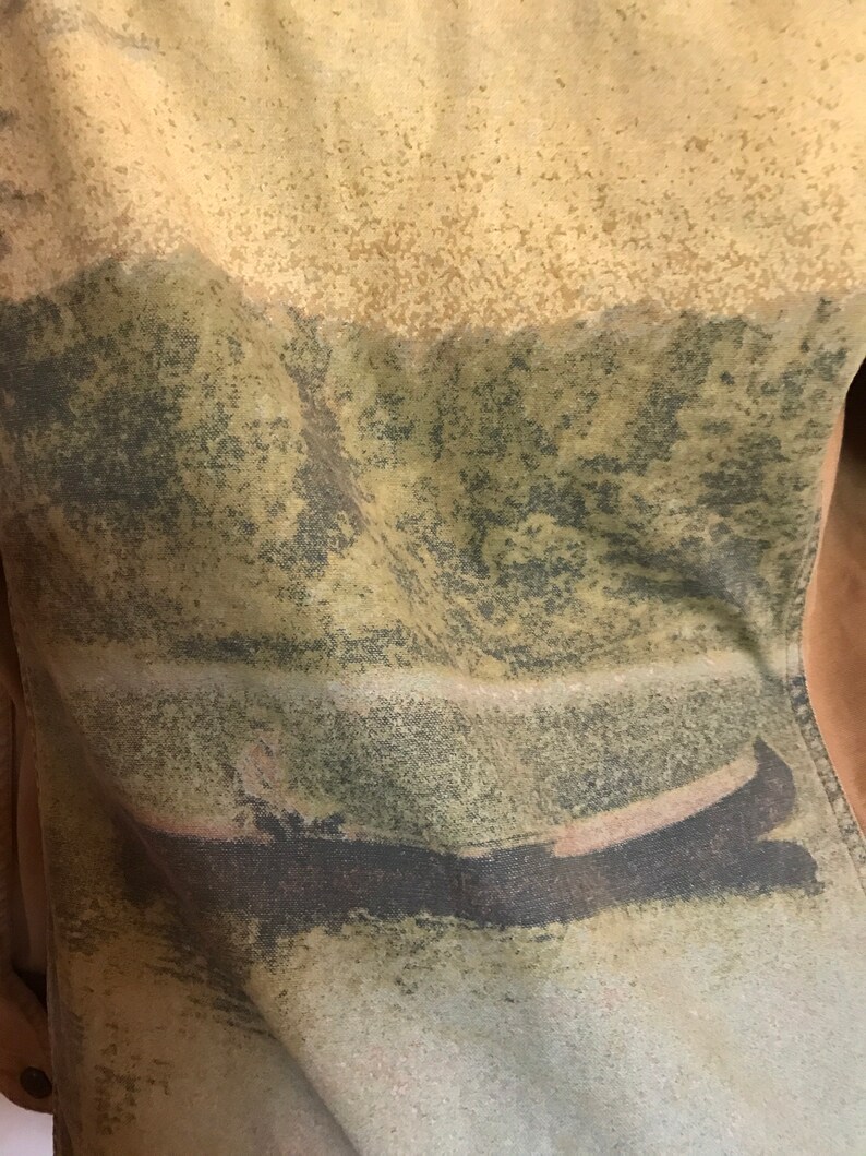 May include: A close-up of a brown, green, and beige fabric with a faded image of a boat on a lake. The fabric has a textured, speckled appearance.