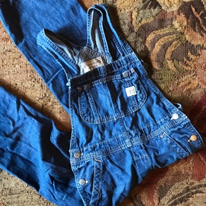 May include: Blue denim overalls with adjustable straps and a patch that says "Polo" on the front.
