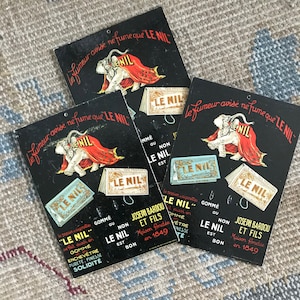 May include: Three vintage black and white advertising cards for "Le Nil" brand rubber erasers. Each card features an elephant with a red scarf and the text "Le fumeur avise ne fume que 'Le Nil'". The cards also include the text "Joseph Bardou et Fils, Maison fondée en 1849" and "Gommé ou non, Le Nil est bon".