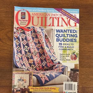 Könnte beinhalten: Eine Ausgabe des Magazins American Patchwork & Quilting, Ausgabe April 2016, mit einem farbenfrohen Quilt auf einem Stuhl. Das Cover enthält Text über Quilting-Freunde und Projekte für jedes Fähigkeitsniveau. Das Magazin liegt auf einer Holzoberfläche.