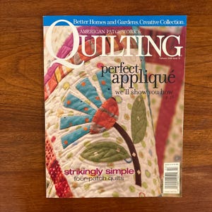 Könnte beinhalten: Das Cover der Zeitschrift "American Patchwork & Quilting" mit einem bunten Quilt mit Blumenmuster. Der Text auf dem Cover lautet "perfect appliqué" und "strikingly simple four-patch quilts".