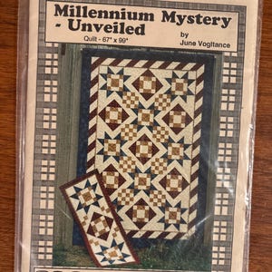May include: A packaged quilt pattern titled "Millennium Mystery - Unveiled" by June Vogitance. The pattern includes a quilt design, 67" x 99", with a geometric pattern in shades of brown, blue, and cream. The brand name "Vogies Patterns" is visible.