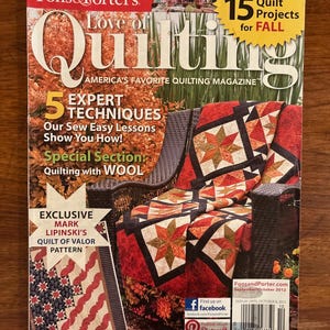 Könnte beinhalten: Das Cover des Magazins "Love of Quilting" zeigt einen Quilt über einem Korbstuhl. Der Text auf dem Cover lautet "15 Quilt-Projekte für den Herbst" und "5 Expertentechniken". Ein kleineres Quiltmuster ist links abgebildet.