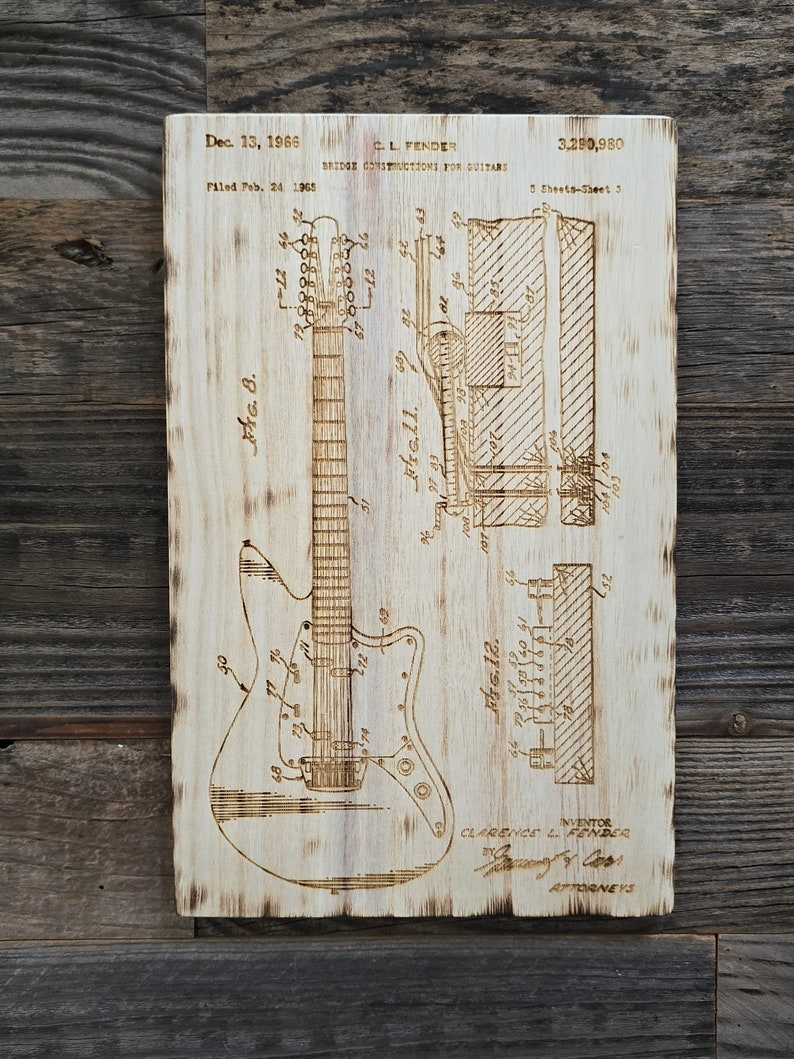 May include: A black and white line drawing of a guitar bridge construction patent. The patent is titled "Bridge Constructions for Guitars" and is dated 13 December 1966. The patent number is 3,290,980. The inventor is Clarence L. Fender.