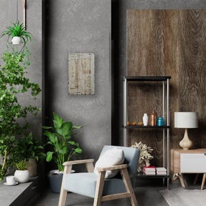 May include: A light blue armchair with a white cushion sits in a modern living room with a wooden shelving unit, a lamp, and a potted plant. The wall behind the chair is a light grey concrete.