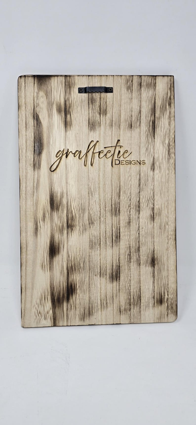 May include: A close-up of a wooden sign with the text "graffetie DESIGNS" burned into the surface. The wood has a distressed, weathered look.