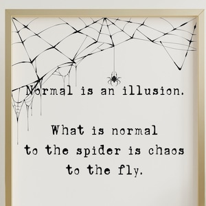 May include: A framed print with a gold border features a spider web design and a quote by Morticia Addams: "Normal is an illusion. What is normal to the spider is chaos to the fly." The words are in black on a white background.