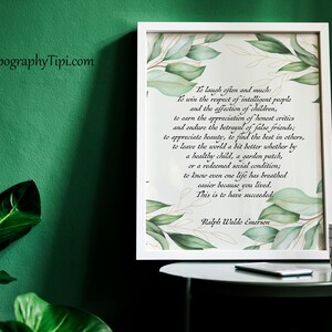 May include: A framed print with a quote by Ralph Waldo Emerson, featuring green leaf accents. A mug with a black grid pattern sits on a small table. The background is a dark green wall.