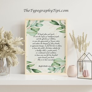 May include: A framed print with a quote by Ralph Waldo Emerson, surrounded by green watercolor leaves. The print is displayed on a white shelf with decorative vases and dried plants. The text reads "To laugh often and much..."