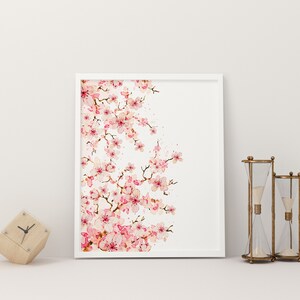 Puede incluir: Una impresi&oacute;n enmarcada en blanco de una pintura de acuarela de una rama de cerezo rosa sobre un fondo blanco.