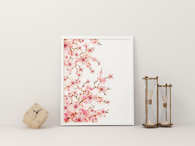 Puede incluir: Una impresi&oacute;n enmarcada en blanco de una pintura de acuarela de una rama de cerezo rosa sobre un fondo blanco.