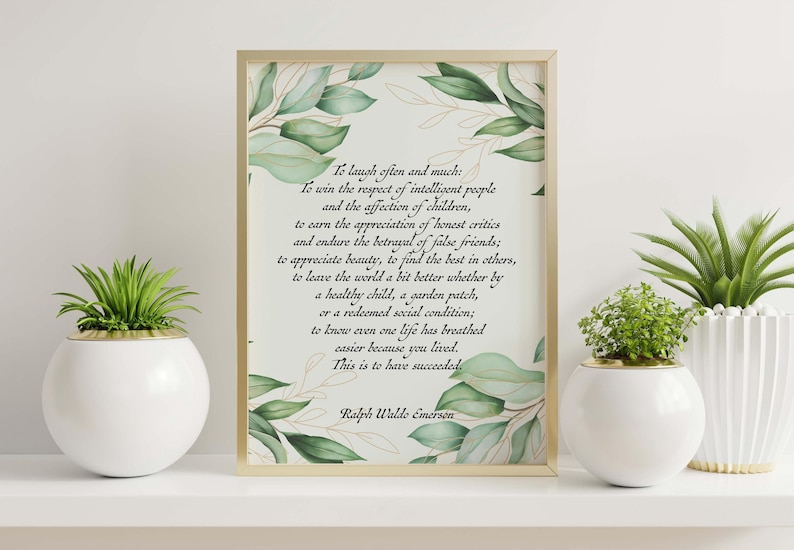 May include: A framed print with a gold border featuring a quote by Ralph Waldo Emerson, surrounded by watercolor-style green leaves. Two white spherical planters with green plants are on either side.