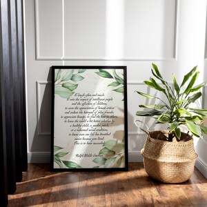 May include: A framed print with a black border features a quote by Ralph Waldo Emerson, surrounded by green and gold leaf illustrations. A woven basket with a green plant sits to the right of the print, adding a natural element to the scene.