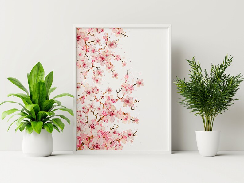 Puede incluir: Una pintura de acuarela enmarcada de una rama de flor de cerezo rosa sobre un fondo blanco.