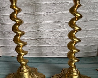 Candelabros antiguos de latón con forma de espiral, posiblemente de época.