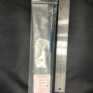 May include: A clear plastic bag containing a set of 10 silver bead making mandrels and a blue and silver bead making tool. The bag is labeled "HOTLINE Beadmaker Mandrels" and includes a list of product numbers and descriptions. A ruler is visible to the right of the bag.
