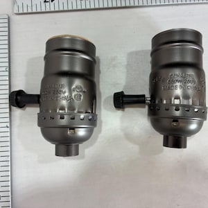 May include: Two gray lamp sockets with black turn knobs. Each socket has the text "ELKELITE 660W 250V MADE IN CHINA". A ruler is in the background.