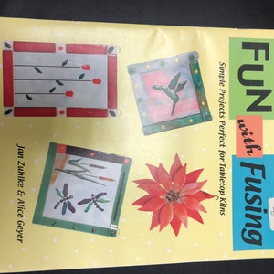 May include: Book cover with the title "FUN with Fusing" and the subtitle "Simple Projects Perfect for Tabletop Kilns". The cover features four fused glass projects: a red flower, a hummingbird, a dragonfly, and a bouquet of red tulips.
