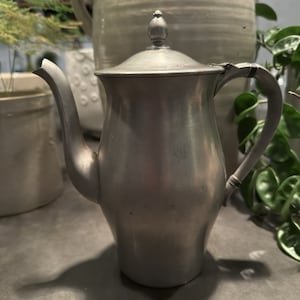 May include: A silver pewter teapot with a rounded body and a lid with a knob on top. The teapot has a spout and a handle.
