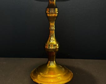 Puede incluir: Un candelabro de metal dorado pulido con una placa superior circular ancha y plana, un tallo central delgado con dos nodos decorativos redondeados distintos y una base circular ancha y estable que se estrecha hacia arriba.