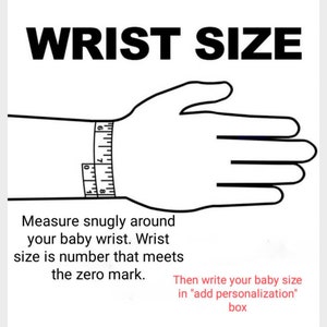 May include: A black and white illustration of a hand with a measuring tape around the wrist. The text "WRIST SIZE" is at the top of the image. The text below the image reads: "Measure snugly around your baby wrist. Wrist size is number that meets the zero mark. Then write your baby size in "add personalization" box."