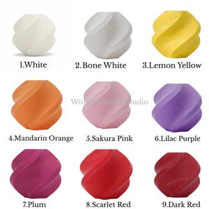 May include: A collection of nine decorative, spherical objects in various colors, each with a unique, swirling design. Colors include white, bone white, lemon yellow, mandarin orange, sakura pink, lilac purple, plum, scarlet red, and dark red. Each object is labeled with its color name.