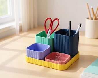 May include: A colorful desk organizer set with a yellow base, holding containers in green, blue, purple, and red. The organizer contains scissors, pens, and paperclips. The containers have a ribbed texture.