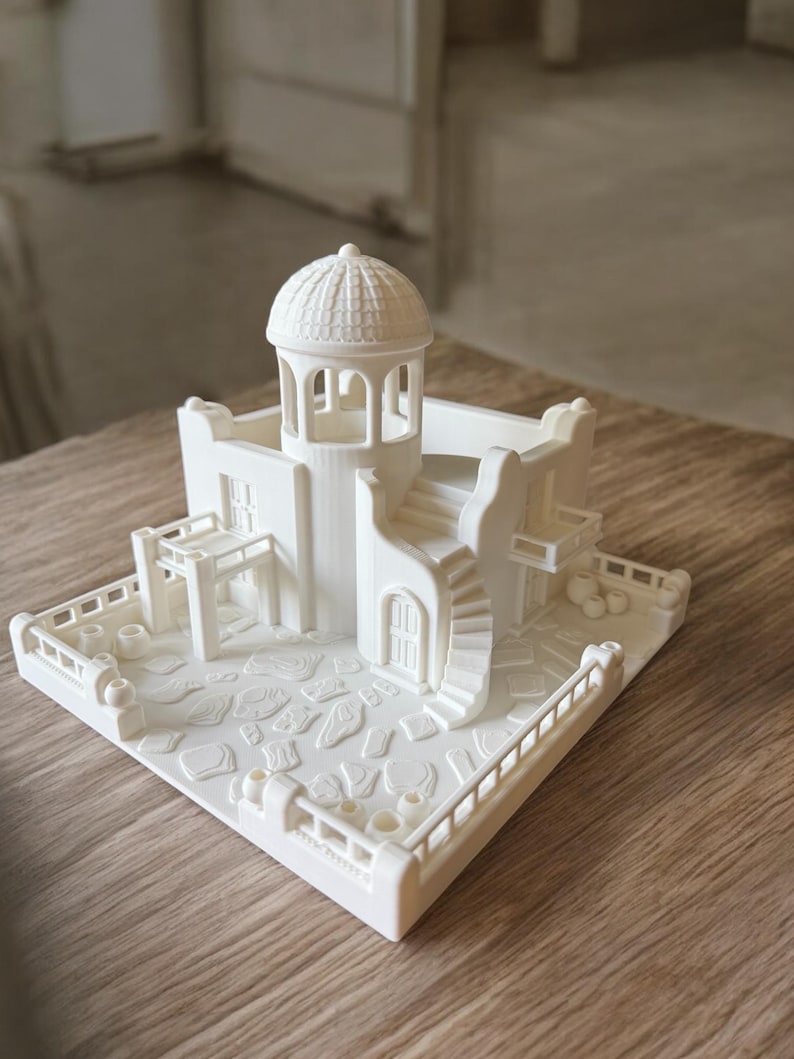 May include: A 3D-printed miniature model of a white building with a domed roof, spiral staircase, and detailed architectural features. The model includes a courtyard with textured paving stones and a surrounding railing.