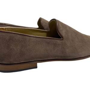 May include: A pair of brown suede loafers with a pointed toe and a leather sole.