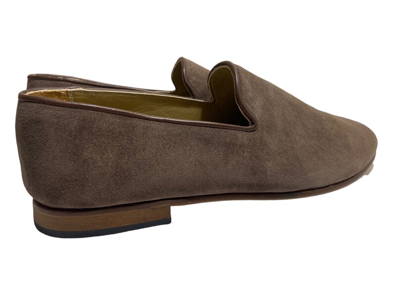 May include: A pair of brown suede loafers with a pointed toe and a leather sole.