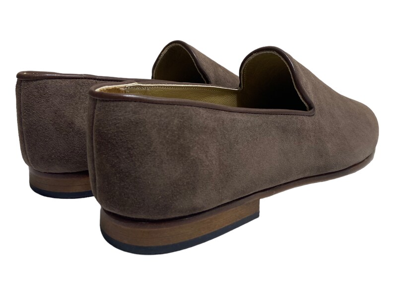 May include: A pair of brown suede loafers with a leather sole. The loafers have a pointed toe and a slip-on design.