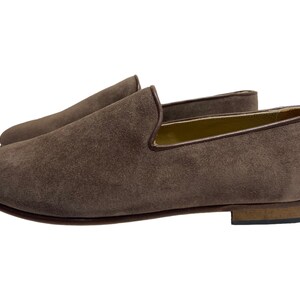 May include: A pair of brown suede loafers with a leather sole. The loafers have a simple design and are perfect for casual wear.