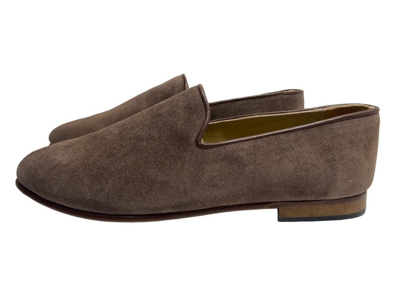 May include: A pair of brown suede loafers with a leather sole. The loafers have a simple design and are perfect for casual wear.